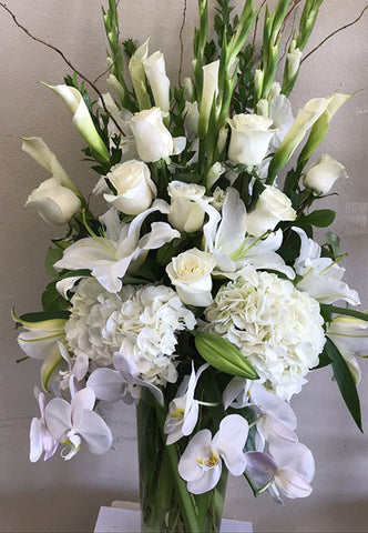 Arrangement of white blooms such as Orchids and Roses with a vase 